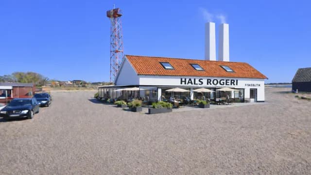 Visualisering af Hals Røgeri og Foreningshus på Østpieren med fiskebutik, skorsten og havnemiljø i baggrunden